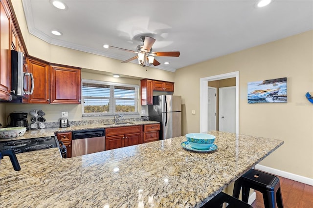 kitchen featuring sink, stainless steel appliances, dark wood-type flooring, kitchen peninsula, and a breakfast bar