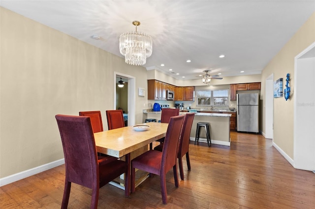 dining area with ceiling fan with notable chandelier and dark hardwood / wood-style flooring