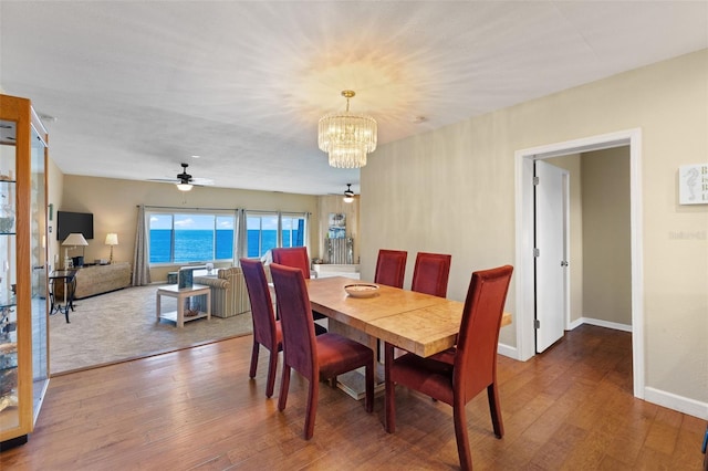 dining area with wood-type flooring and ceiling fan with notable chandelier