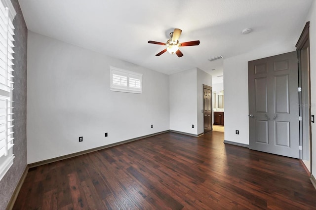 unfurnished bedroom with ceiling fan, ensuite bath, and dark hardwood / wood-style flooring