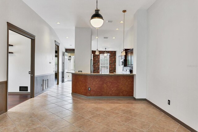 kitchen with light tile patterned flooring, hanging light fixtures, and stainless steel refrigerator