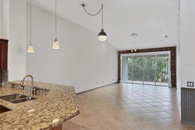 kitchen with light tile patterned floors, sink, hanging light fixtures, high vaulted ceiling, and light stone countertops