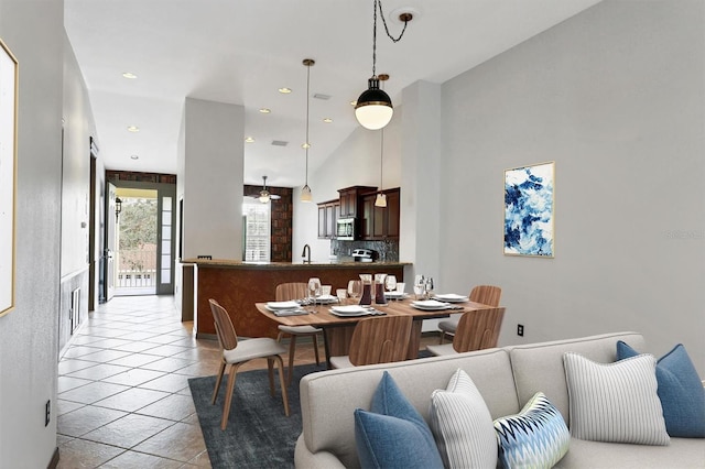 tiled dining space featuring sink and a high ceiling