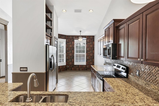 kitchen featuring lofted ceiling, sink, light tile patterned floors, stainless steel appliances, and decorative light fixtures