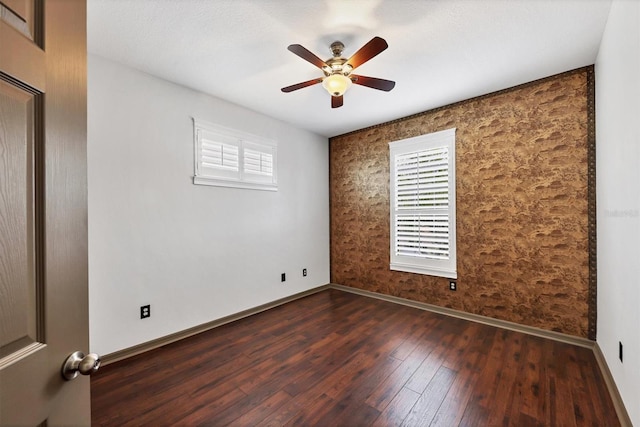 empty room with ceiling fan and dark hardwood / wood-style flooring