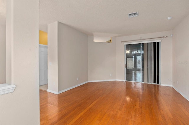 spare room featuring wood-type flooring and a textured ceiling