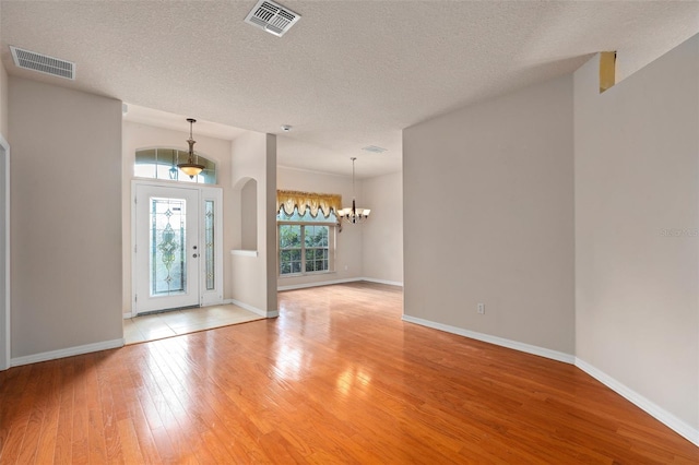 entryway with a chandelier, hardwood / wood-style floors, and a textured ceiling