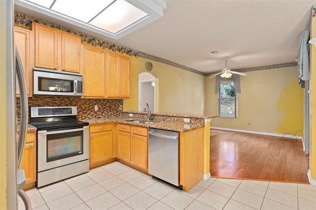 kitchen featuring ceiling fan, sink, stainless steel appliances, kitchen peninsula, and light wood-type flooring