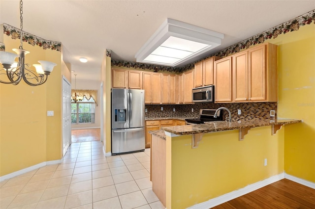 kitchen featuring dark stone counters, kitchen peninsula, a breakfast bar area, and stainless steel appliances