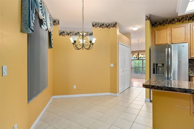 kitchen with stainless steel fridge, decorative light fixtures, an inviting chandelier, and light tile patterned flooring