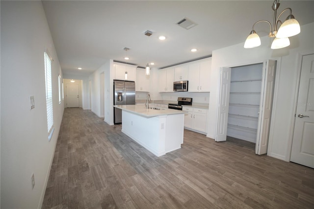 kitchen with hanging light fixtures, sink, stainless steel appliances, and wood-type flooring