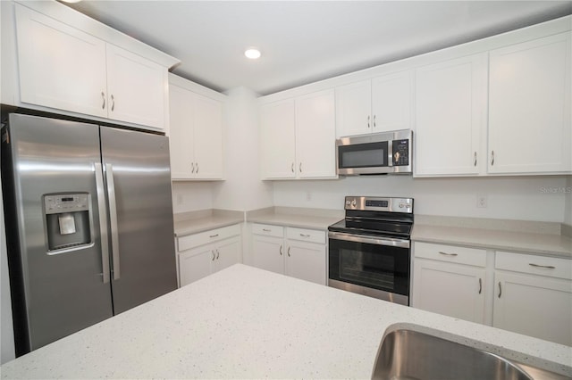 kitchen featuring white cabinets, light stone counters, and appliances with stainless steel finishes