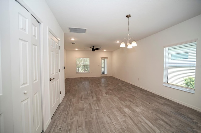 unfurnished room featuring wood-type flooring and ceiling fan with notable chandelier