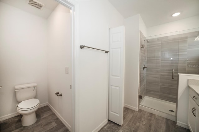 bathroom featuring vanity, toilet, wood-type flooring, and a shower with door