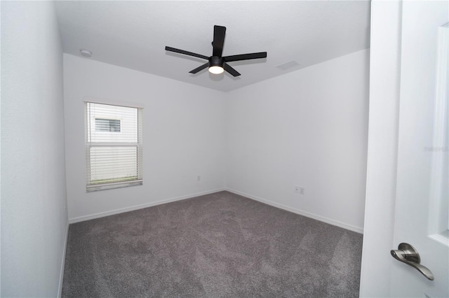 spare room featuring dark carpet and ceiling fan