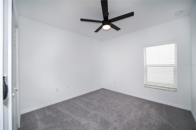 spare room featuring ceiling fan and dark carpet