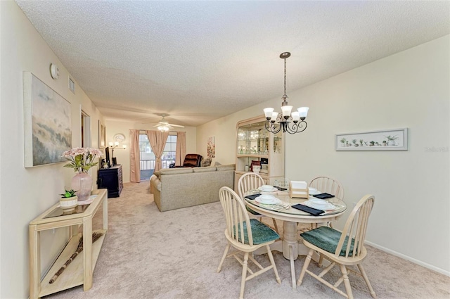 dining room with ceiling fan with notable chandelier, light colored carpet, and a textured ceiling