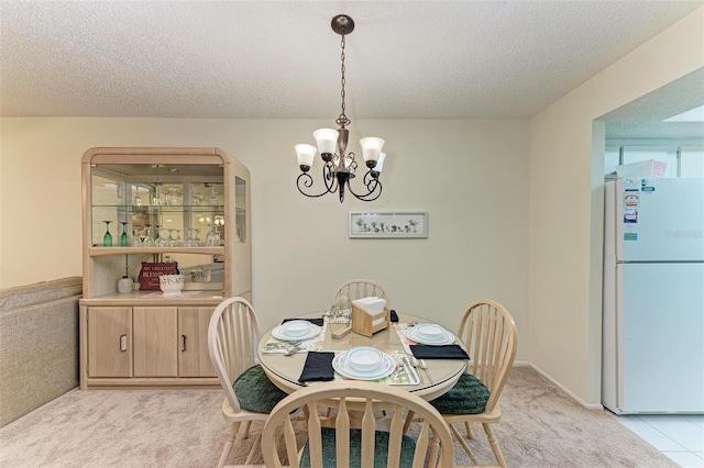 carpeted dining room with a textured ceiling and an inviting chandelier