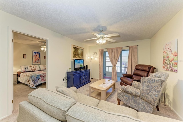 living room with ceiling fan, light colored carpet, and a textured ceiling