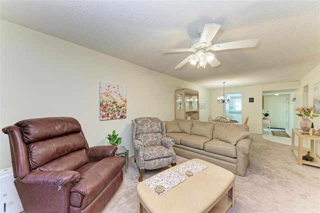 living room featuring light carpet, a textured ceiling, and ceiling fan with notable chandelier