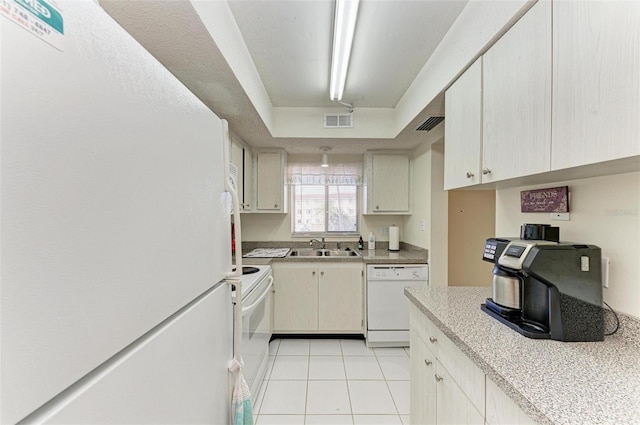 kitchen featuring light tile patterned flooring, white appliances, sink, and cream cabinets