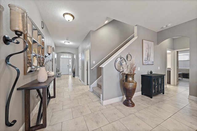 foyer entrance featuring a textured ceiling, a healthy amount of sunlight, and light tile patterned flooring