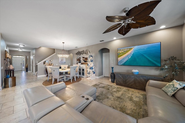 living room with ceiling fan with notable chandelier and light tile patterned floors