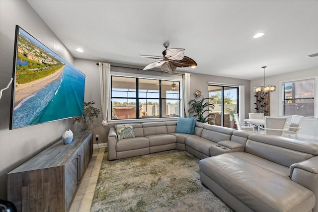 living room featuring ceiling fan with notable chandelier and light tile patterned flooring