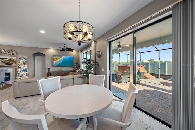 tiled dining space featuring ceiling fan with notable chandelier and a wealth of natural light