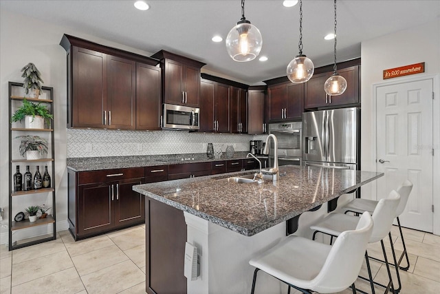 kitchen with sink, hanging light fixtures, an island with sink, a kitchen bar, and appliances with stainless steel finishes