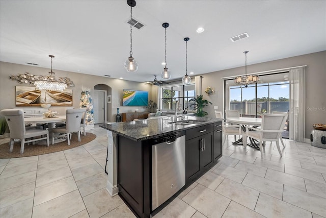 kitchen featuring a center island with sink, dishwasher, plenty of natural light, and dark stone counters