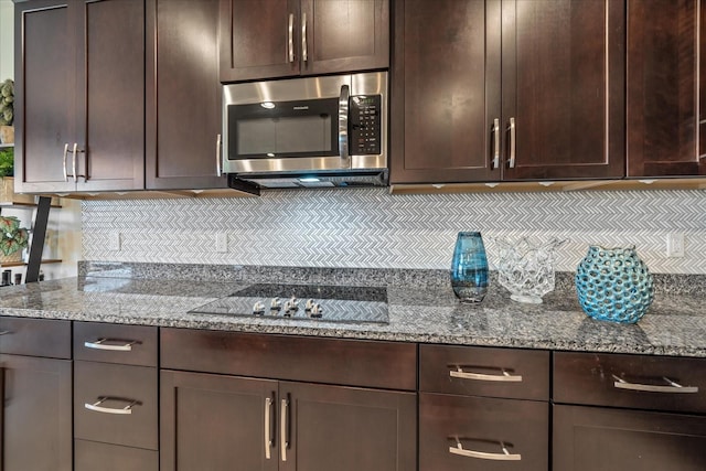 kitchen featuring light stone countertops, dark brown cabinets, black cooktop, and tasteful backsplash