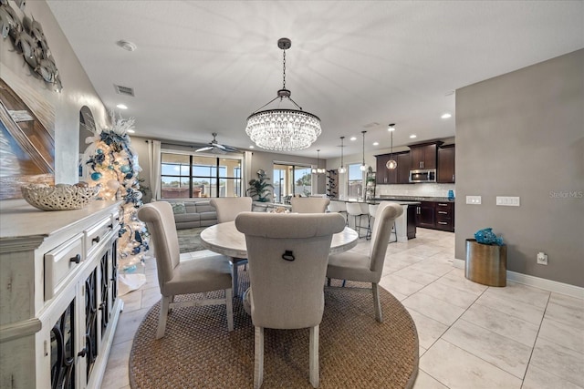 dining space with ceiling fan with notable chandelier and light tile patterned flooring