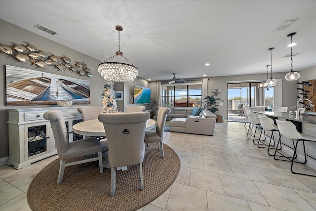 dining area with sink, light tile patterned floors, and ceiling fan with notable chandelier