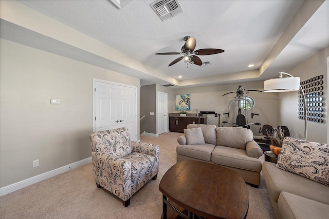 carpeted living room with ceiling fan, a raised ceiling, and a textured ceiling