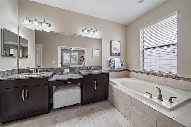 bathroom with vanity, a healthy amount of sunlight, and tiled tub