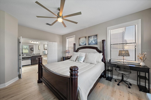 bedroom featuring ceiling fan, ensuite bathroom, and light wood-type flooring