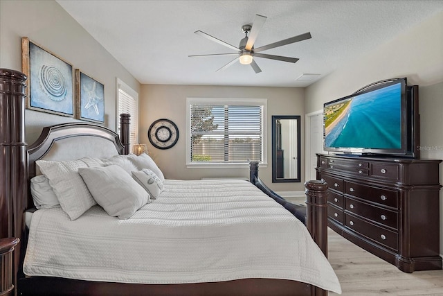 bedroom featuring ceiling fan, light hardwood / wood-style floors, and a textured ceiling