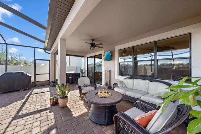 view of patio / terrace featuring a grill, ceiling fan, a lanai, and an outdoor living space with a fire pit