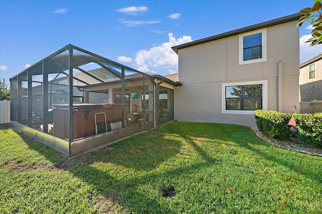 rear view of property featuring a lanai, a yard, and a hot tub