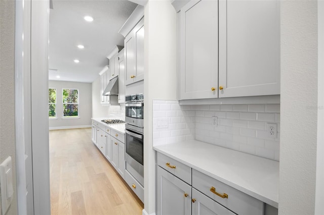 kitchen with light wood-type flooring, backsplash, white cabinets, and stainless steel gas cooktop