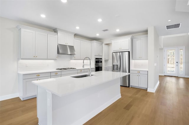 kitchen featuring sink, an island with sink, light hardwood / wood-style flooring, and appliances with stainless steel finishes