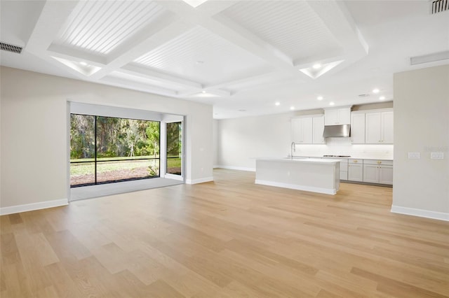 unfurnished living room with beam ceiling, light hardwood / wood-style flooring, coffered ceiling, and sink