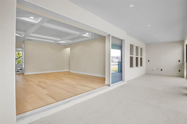 empty room with beamed ceiling, hardwood / wood-style floors, and coffered ceiling