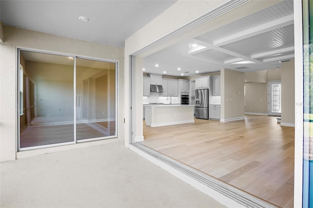 unfurnished living room featuring sink, beamed ceiling, and coffered ceiling