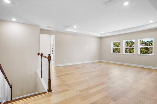 unfurnished room featuring a tray ceiling and light hardwood / wood-style floors