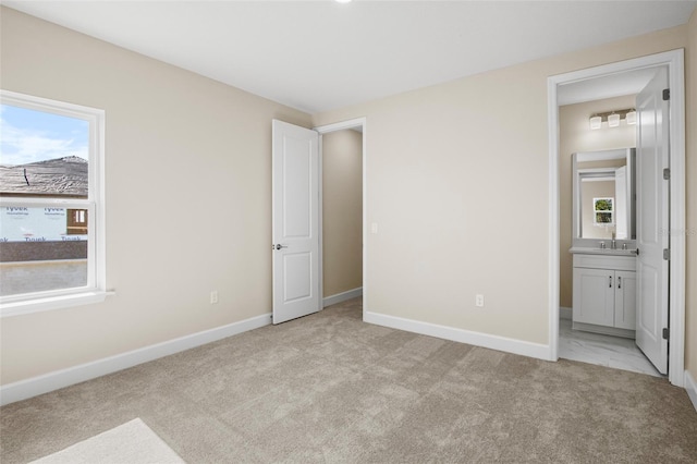 unfurnished bedroom featuring multiple windows, light carpet, and ensuite bath