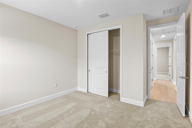 unfurnished bedroom with a closet and light colored carpet