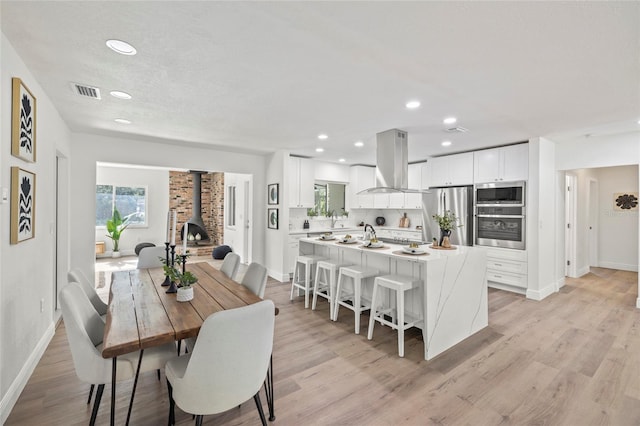 dining room with light hardwood / wood-style floors and a wood stove