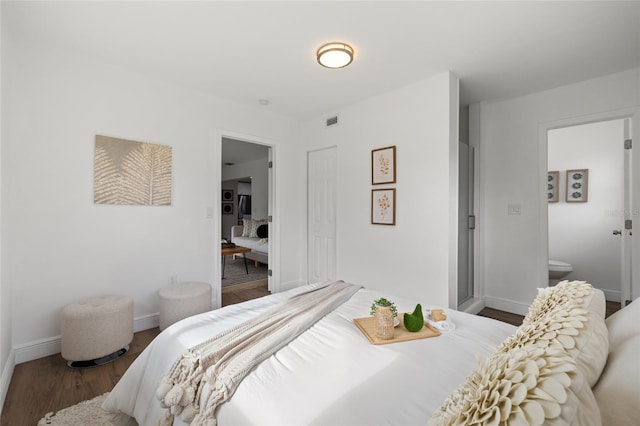 bedroom with ensuite bath and wood-type flooring